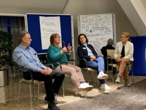 4 Menschen sitzen gemeinsam in einer Posiumsdiskussion.
